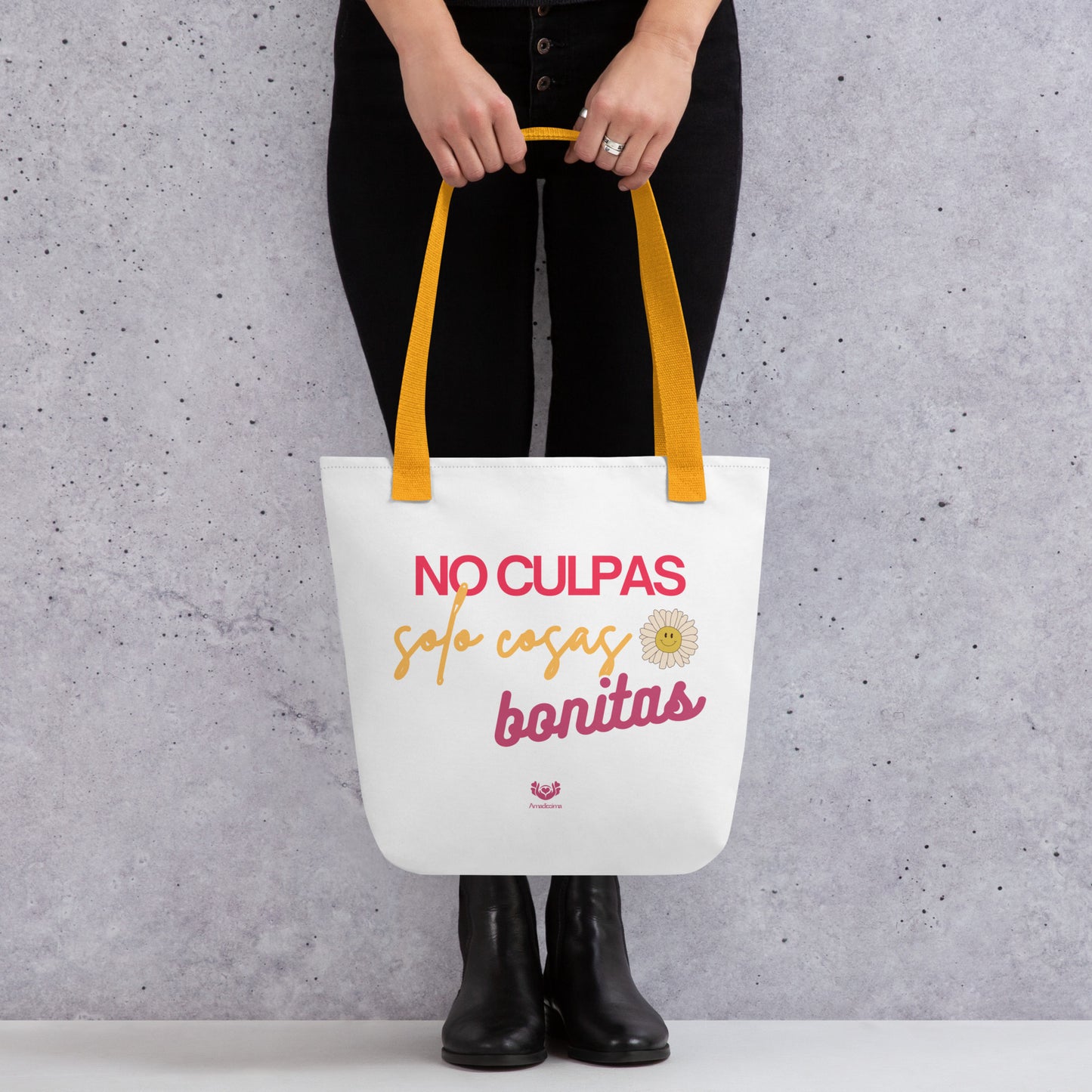 Bolsa tote “No culpas, solo cosas bonitas” con asas amarillas, vista frontal con manos sosteniéndola.