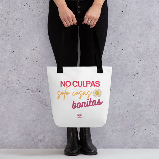Bolsa tote “No culpas, solo cosas bonitas” con asas negras, vista frontal con manos sosteniéndola