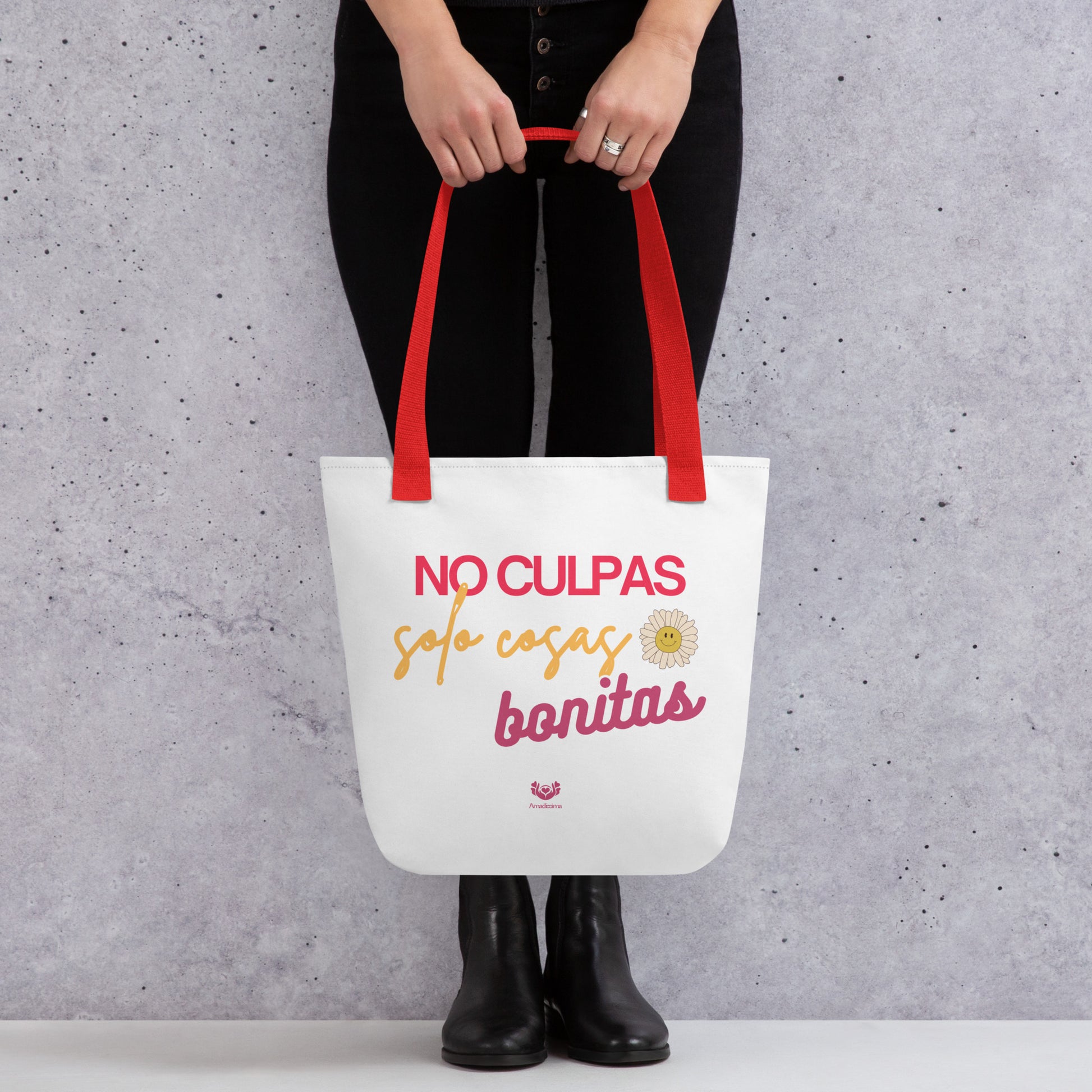 Bolsa tote “No culpas, solo cosas bonitas” con asas rojas, vista frontal con manos sosteniéndola